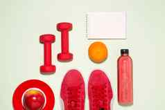 健身概念运动鞋苹果哑铃水果汁瓶柔和的颜色背景