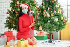 肖像高加索人女人卫生面具相机坐房间装修圣诞节树庆祝节日科维德流感大流行保持首页正常的生活方式