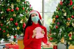 女人卫生面具持有粉红色的针织他快乐坐着圣诞节树礼物盒子庆祝流感大流行科维德