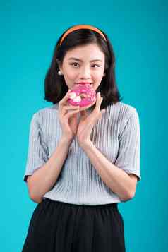 亚洲美女孩持有粉红色的甜甜圈复古的快乐的女人糖果甜点站蓝色的背景