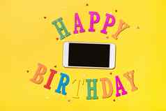 单词快乐生日蛋糕智能手机黄色的背景