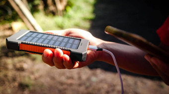 可充电移动权力包太阳能面板年轻的女旅行者的手特写镜头连接充电移动平板电脑聪明的电话