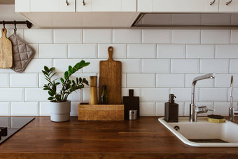 厨房黄铜餐具老板配件挂厨房白色瓷砖墙木桌面绿色植物厨房背景