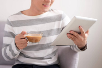 技术人休闲概念英俊的男人。平板电脑电脑杯喝咖啡茶首页