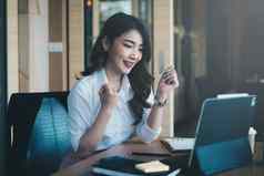 兴奋亚洲女人坐在工作站狂喜的收到了工作提供面试电子邮件移动PC