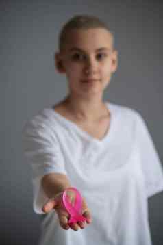 不知名的女人穿白色t恤持有粉红色的丝带象征乳房癌症白色背景