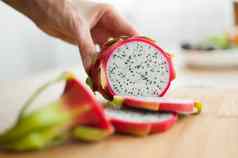 女手切割龙水果火龙果粉红色的皮肤白色纸浆黑色的种子木减少董事会表格异国情调的水果健康的吃概念