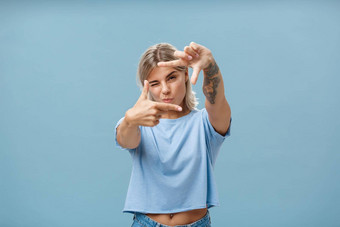 艺术有<strong>创意</strong>的女设计师时尚的t恤关闭眼睛折叠唇使框架手势采取测量想象蓝色的<strong>墙</strong>