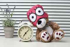 棕色（的）泰迪熊坐在绷带睡觉白色表格报警时钟时间早....