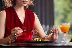 年轻的女人吃新鲜的虾沙拉午餐奢侈品餐厅健康的生活方式饮食概念