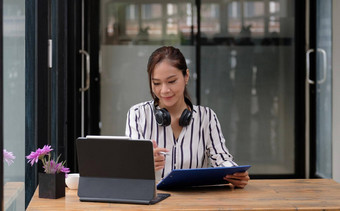 微笑亚洲年轻的女耳机移动PC屏幕听学习在线课程快乐中国人业务女人耳机视频调用客户服务