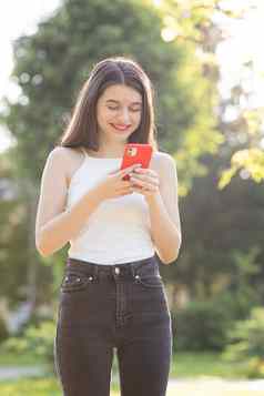女孩笑阅读智能手机快乐的年轻的女人沟通智能手机走公园