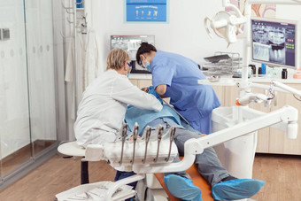 高级牙医女人执行手术把植入物生病的男人。口
