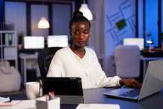 过度劳累非洲女商人检查图表平板电脑