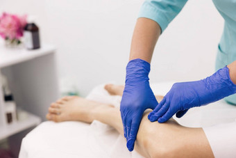 理疗师工人女人协助物理医疗锻炼复苏受伤医生手套检查痛苦的膝盖女病人腿创伤医疗保健医疗保险概念