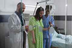 非洲式发型美国阿斯坦特帮助生病的女人站床上持有静脉注射流体滴袋