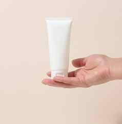 女手持有空白色塑料管化妆品包装奶油过来这里血清广告产品促销活动模拟