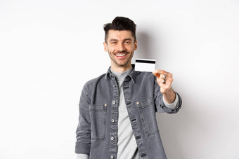 英俊的时尚的的家伙显示塑料信贷卡微笑满意客户端站白色背景