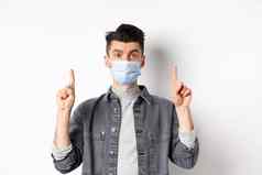 流感大流行生活方式医疗保健医学概念时尚的现代男人。医疗面具显示广告指出手指标志站白色背景