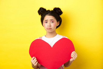 心碎的亚洲女人显示大红色的心断路伤心感觉孤独的情人一天显示情人节卡相机黄色的背景