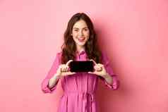 技术概念年轻的有吸引力的女人显示智能手机屏幕水平介绍在线应用程序促销文本站粉红色的背景