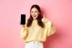 好应用程序微笑满意女人显示拇指空智能手机屏幕推荐应用程序网站站粉红色的背景