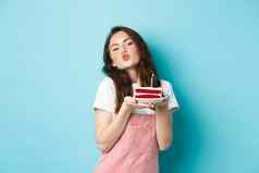 假期庆祝活动可爱的愚蠢的女孩使生日蛋糕使接吻脸庆祝生日站快乐的蓝色的背景