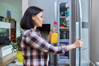 女人打开<strong>冰箱首页</strong>厨房持有瓶橙色汁