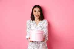 可爱的亚洲女人祝贺假期生日给礼物可爱的盒子站粉红色的背景