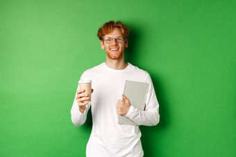 英俊的年轻的男人。员工移动PC喝咖啡打破微笑满意站绿色背景