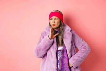 时尚购物概念时尚的亚洲中年女人时尚冬天衣服气味坏挥舞着手鼻子恶心的臭粉红色的背景