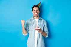 快乐的男人。快乐庆祝生日聚会，派对他持有生日蛋糕使拳头泵站蓝色的背景