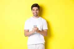 男人。微笑快乐阅读促销提供智能手机站黄色的背景白色t恤