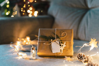 圣诞节自然生态礼物盒子空标签标签发光的光散景松柏科的分支冬天假期模拟灰色的沙发上背景舒适的首页浪费塑料免费的在室内植物