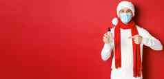 概念科维德圣诞节假期流感大流行英俊的快乐男人。圣诞老人他医疗面具推荐手洗手液站红色的背景