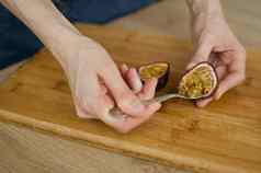 女吃新鲜的有机成熟的granadilla黄色的激情水果勺子异国情调的水果健康的吃概念