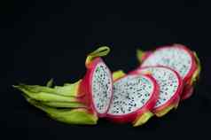片龙水果火龙果粉红色的皮肤白色纸浆种子黑色的背景异国情调的水果健康的吃概念