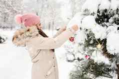美丽的女人温暖的冬天衣服装修圣诞节树公园雪一天