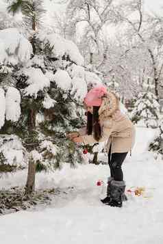 美丽的女人温暖的冬天衣服装修圣诞节树公园雪一天