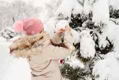 美丽的女人温暖的冬天衣服装修圣诞节树公园雪一天