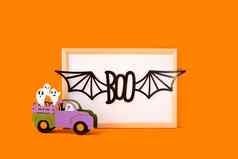 快乐万圣节假期概念万圣节手工制作的纸装饰鬼魂车嘘文本蝙蝠翅膀框架橙色背景万圣节节日聚会，派对问候卡