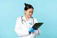 微笑亚洲医生护士写作剪贴板站医疗统一的蓝色的背景