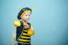小有趣的男孩蜜蜂服装可爱的男孩穿着狂欢节服装可爱的蜜蜂吃蜂蜜服装狂欢节孤立的蓝色的