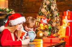 年轻的妈妈。帮助儿子写信圣诞老人冬天假期童年概念圣诞节树助手圣诞老人圣诞节魔法礼物快乐假期概念