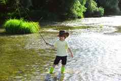 孩子钓鱼孩子学习鱼持有杆河男孩渔夫钓鱼杆年轻的男人。飞钓鱼