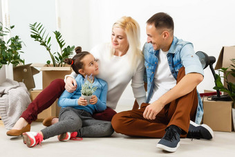 快乐家庭坐着木地板上父亲妈妈。孩子有趣的移动房子一天首页设计室内概念