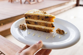 胡萝卜南瓜蛋糕咖啡奶油减少板美味的切片胡萝卜蛋糕片蛋糕白色陶瓷板手装饰核桃