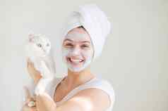 女人毛巾头发粘土面具脸持有白色毛茸茸的猫白色背景复制空间