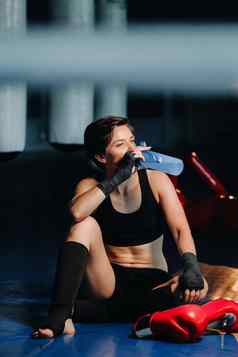 肖像女拳击手红色的手套健身房锻炼瓶水