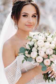 美丽的新娘婚礼衣服花束前盐山惊人的年轻的新娘卷曲的头发婚礼一天美丽的肖像新娘新郎